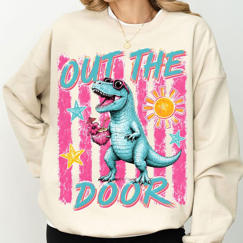 May include: Beige sweatshirt featuring a turquoise dinosaur wearing sunglasses, holding a tropical drink, and the words "OUT THE DOOR" in turquoise and pink. Pink and white striped background with star and sun graphics.