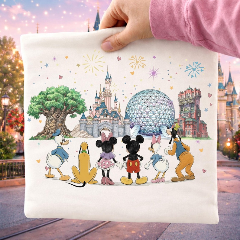 May include: A white tote bag featuring a colorful illustration of Disney characters and landmarks. The design includes Donald Duck, Pluto, Minnie Mouse, Mickey Mouse, Daisy Duck, and Goofy, with fireworks and iconic park structures.