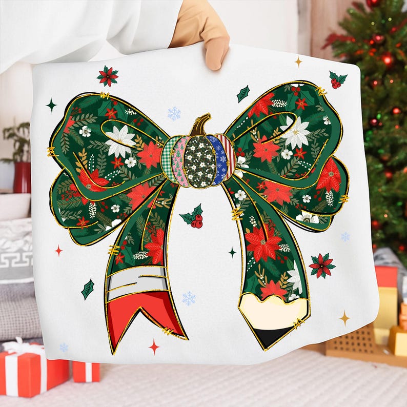 May include: A white pillow with a large bow design. The bow is green with red poinsettias and white flowers. A pumpkin is in the center of the bow. Gold trim outlines the bow. The pillow is held by a person.