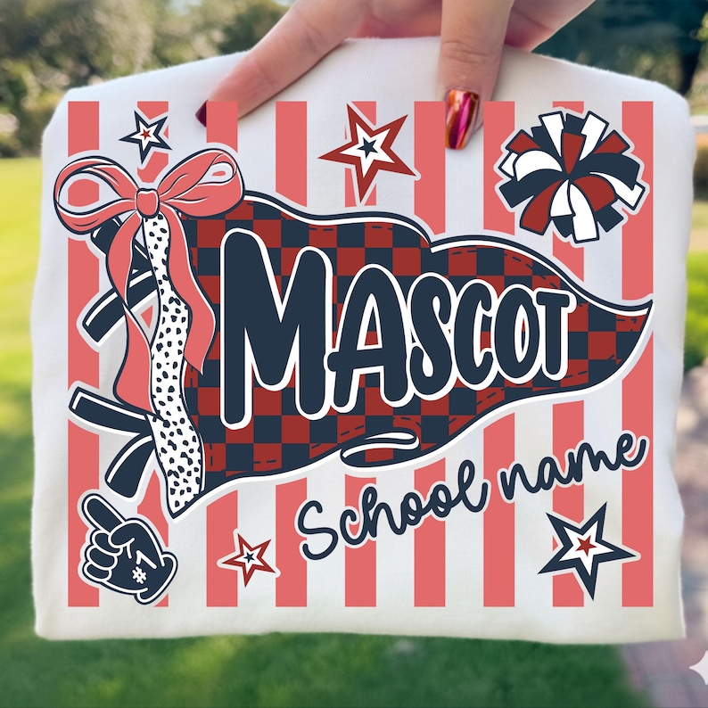 May include: A white t-shirt featuring a graphic print with vertical coral stripes. The design includes a dark blue pennant with a red and black checkered pattern, the text MASCOT and School name, a coral bow, a cheerleader pom-pom, stars, and a foam finger.