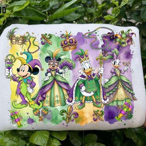 May include: White fabric featuring a colorful Mardi Gras design with Disney characters Mickey Mouse, Minnie Mouse, Donald Duck, and Daisy Duck in festive attire. The design includes masks, crowns, and fleur-de-lis.