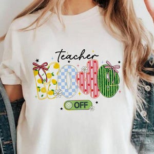 Op de afbeelding: Wit T-shirt met het woord "Teacher" boven het woord "Mode". De letters zijn versierd met citroenen, een blauw geblokt patroon, roze hartjes en watermeloenstrepen. Een groene "ON OFF" knop staat eronder.