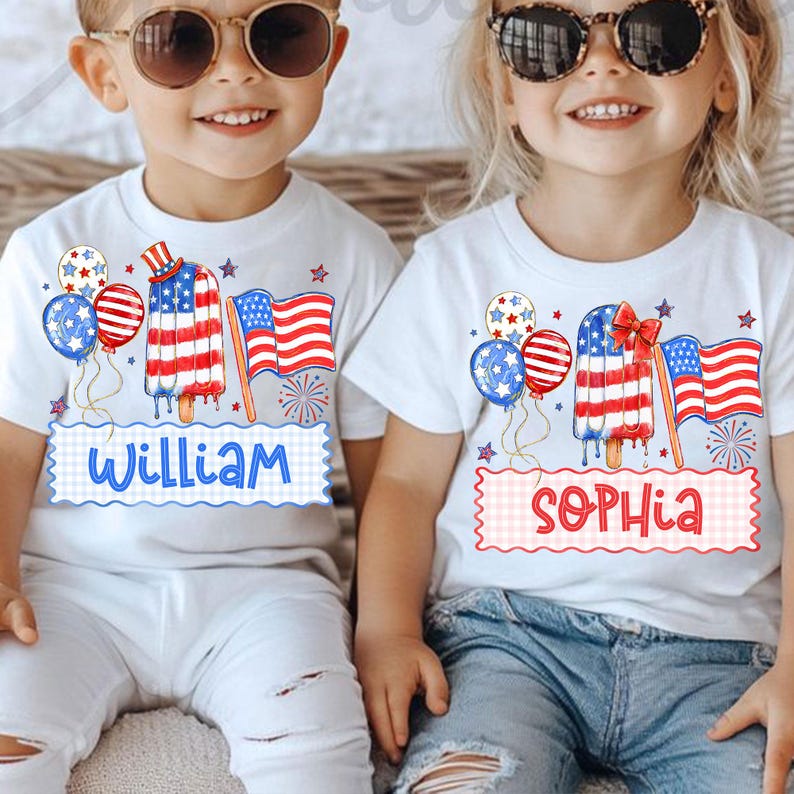 May include: Two white t-shirts with patriotic designs. One shirt has the name "William" and the other has "Sophia". Each shirt features a popsicle, balloons, and an American flag. The popsicle design has red, white, and blue colours.