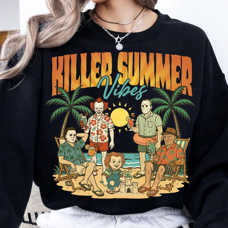 May include: Black sweatshirt with a graphic featuring horror movie characters on a beach, palm trees, and the text "KILLER SUMMER Vibes" in orange and blue. The design includes a sun and sandcastles.