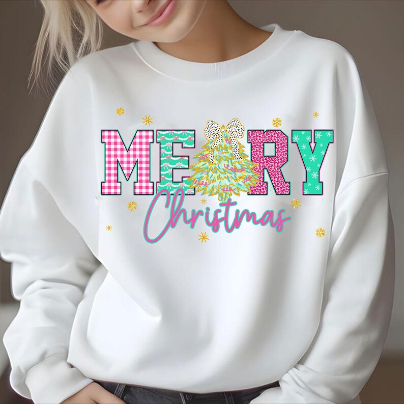 Puede incluir: Sudadera blanca con un gr&aacute;fico colorido de "MERRY Christmas". Las letras son de cuadros rosas, turquesa y rosa brillante. Un &aacute;rbol de Navidad y copos de nieve tambi&eacute;n est&aacute;n presentes en el dise&ntilde;o. Una prenda superior festiva.