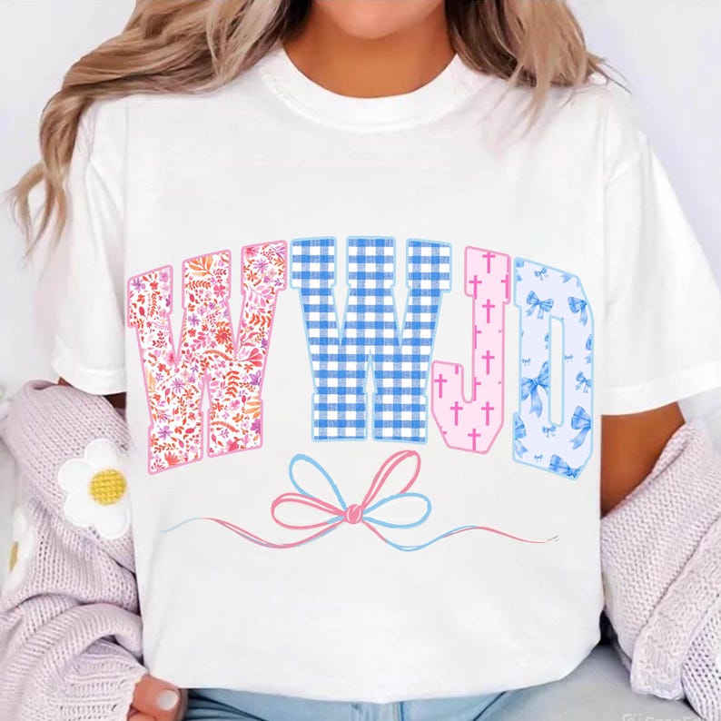 May include: White t-shirt with the text "WWJD" in a variety of patterns. The "W" is floral, the "W" is blue gingham, the "J" is pink with crosses, and the "D" is blue with bows. A pink and blue bow is below the text.