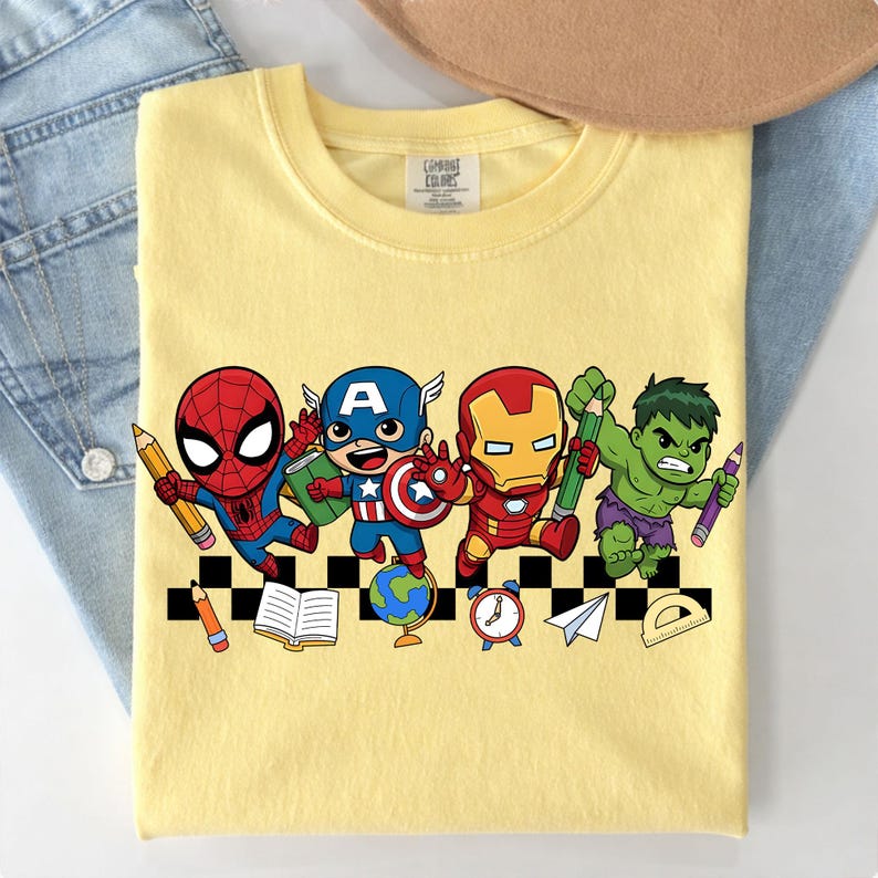 May include: Yellow t-shirt featuring cartoon illustrations of Spider-Man, Captain America, Iron Man, and the Hulk, each holding a pencil. The design includes school-themed elements like a globe, books, and a clock.