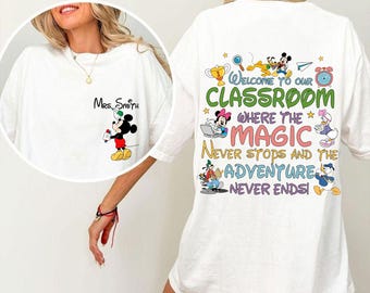 May include: White t-shirt featuring Mickey Mouse holding a pen with "Mrs. Smith" above. The back of the shirt has the text "Welcome to our Classroom" with various Disney characters and the phrases "Where the Magic Never Stops and the Adventure Never Ends!"