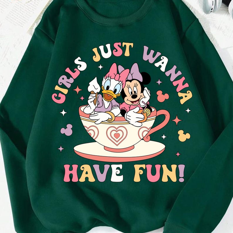 May include: Green sweatshirt with a graphic of Disney's Minnie Mouse and Daisy Duck sitting in a teacup. The text "Girls Just Wanna Have Fun!" is printed in rainbow colors.