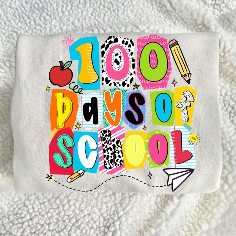 May include: A light gray sweatshirt with a colorful graphic that reads "100 Days of School." The design includes an apple, pencil, and paper airplane. The text is in various colors and fonts.