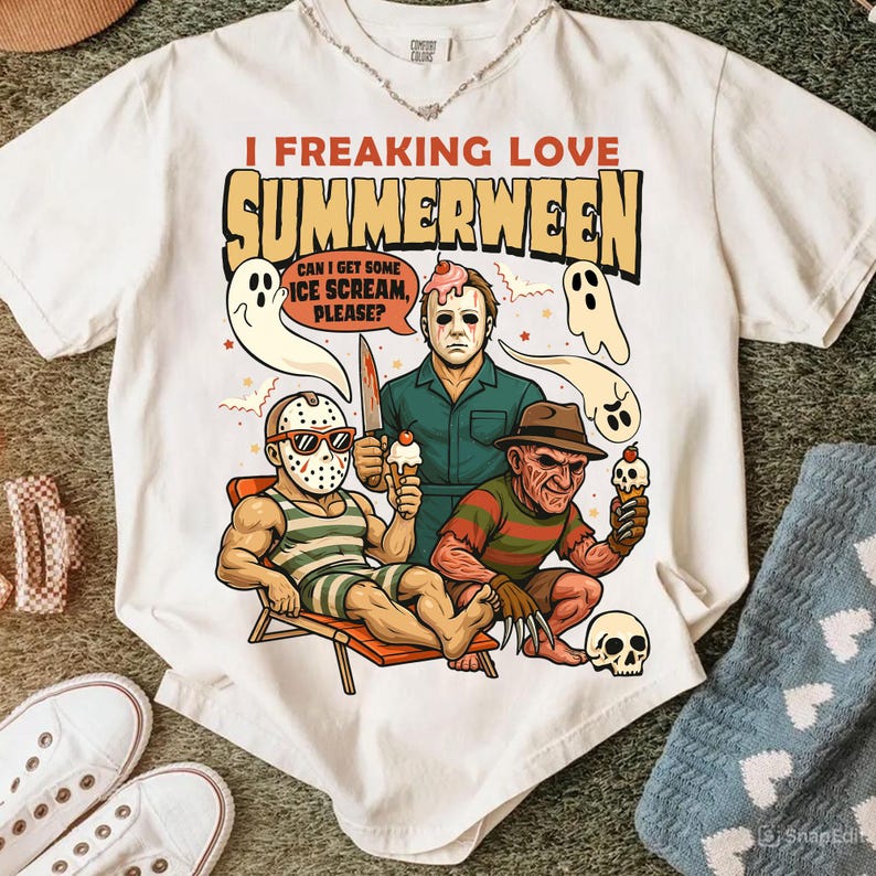 May include: White t-shirt with a graphic featuring horror movie characters holding ice cream cones. Text reads "I Freaking Love Summerween" with a speech bubble saying "Can I get some ice scream, please?"