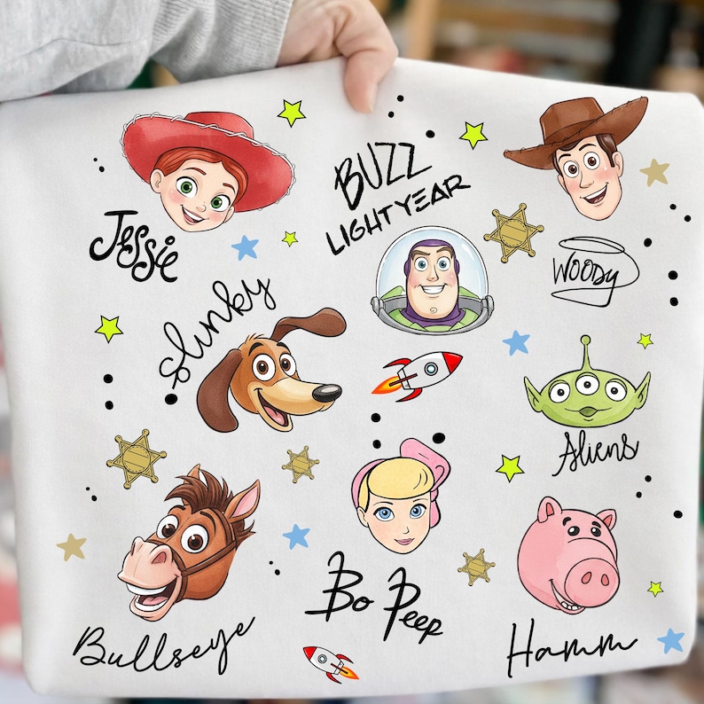 May include: White fabric with colourful illustrations of characters from the animated film "Toy Story." Includes images of Jessie, Buzz Lightyear, Woody, Slinky, Aliens, Bo Peep, Bullseye, and Hamm, with their names written in cursive.