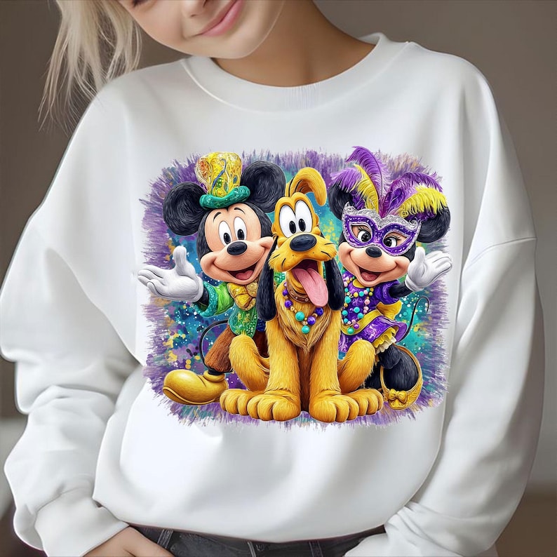 K&ouml;nnte beinhalten: Wei&szlig;es Sweatshirt mit einem farbenfrohen Design von Mickey Mouse, Pluto und Minnie Mouse in Mardi-Gras-Kost&uuml;men. Mickey tr&auml;gt Gr&uuml;n und Gold, Pluto eine Halskette und Minnie eine lila Maske. Das Bild hat einen bunten Hintergrund.