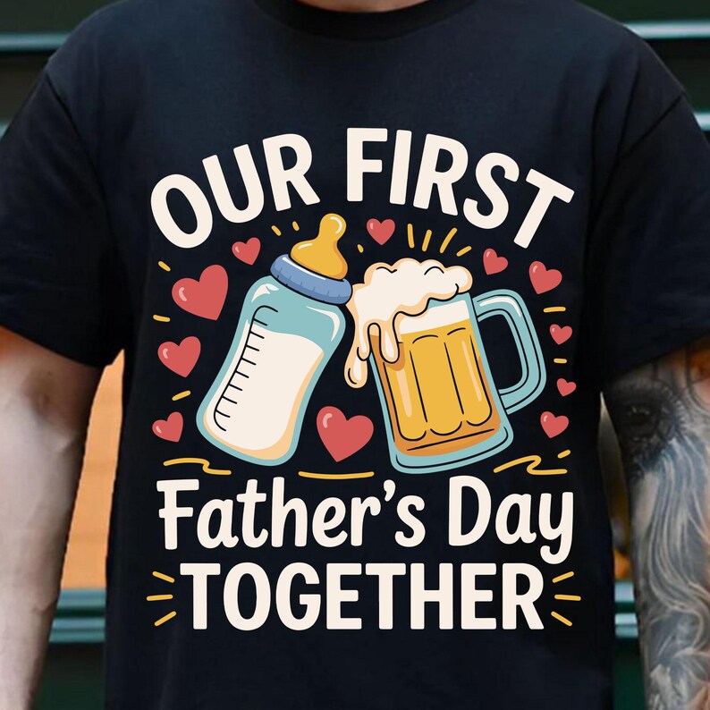 May include: Black t-shirt with a graphic design of a baby bottle and a beer glass with the text "Our First Father's Day Together" in white.