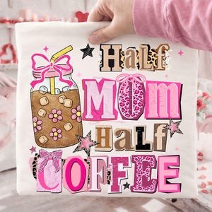May include: A white t-shirt featuring a graphic of an iced coffee drink in a mason jar with a pink bow and straw. The text "Half Mom Half Coffee" is displayed in various fonts and colors, with star accents.