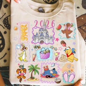 May include: Beige t-shirt with colorful cartoon illustrations of Disney characters and summer-themed elements. The design includes a castle, the word "Summer", the year "2026", and various characters like Winnie the Pooh and Tigger.