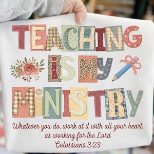 Pode incluir: Camisola branca com a frase "TEACHING IS MY MINISTRY" em letras coloridas e em estilo patchwork. Inclui um desenho de lápis e detalhes florais. A parte inferior da camisa tem o versículo bíblico Colossenses 3:23.