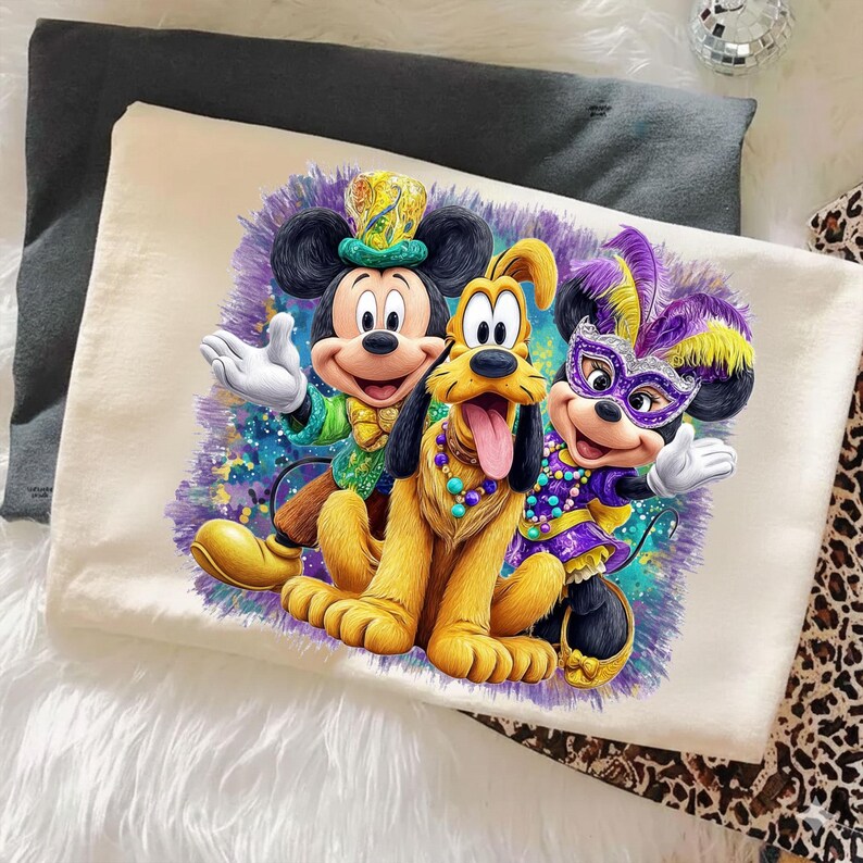 K&ouml;nnte beinhalten: Ein cremefarbenes Kissenbezug mit einem farbenfrohen Motiv von Mickey Mouse, Pluto und Minnie Mouse. Mickey tr&auml;gt einen gr&uuml;nen und goldenen Hut, Pluto eine Perlenkette und Minnie eine lila Maske und ein lila-gelbes Outfit. Auf lila Hintergrund.