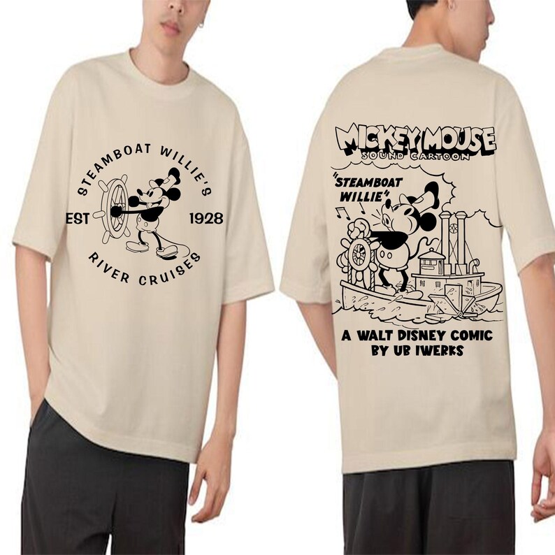May include: Two beige t-shirts featuring a black and white graphic print of Mickey Mouse on a steamboat. The text on the shirts reads "Mickey Mouse Sound Cartoon", "Steamboat Willie", "A Walt Disney Comic by Ub Iwerks", and "Steamboat Willie's Est 1928 River Cruises".