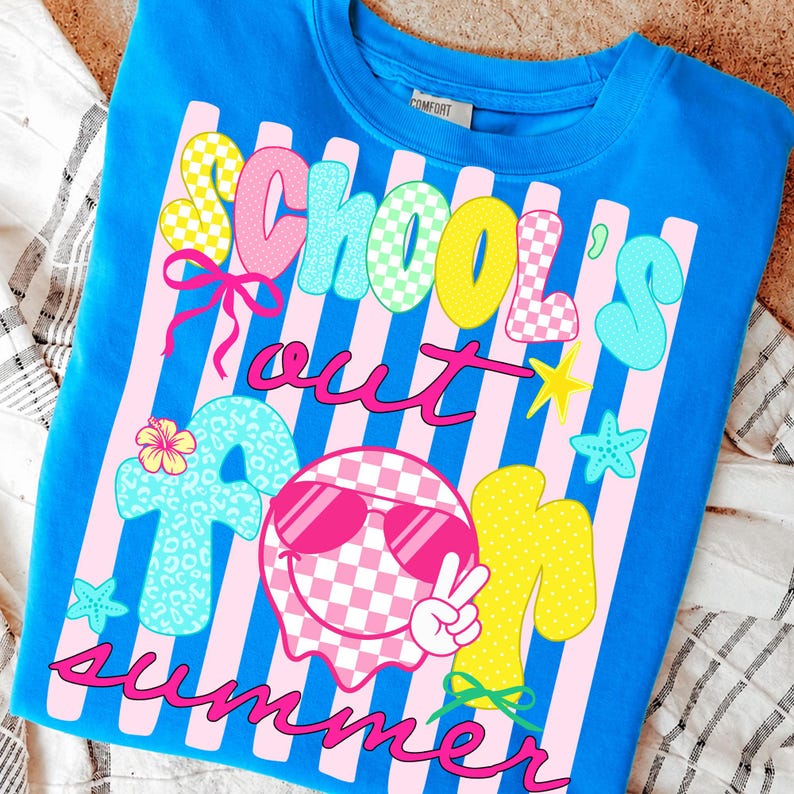 May include: A blue t-shirt with the words "School's Out For Summer" in a colorful, playful font. The design includes pink stripes, stars, and a smiley face wearing sunglasses. The shirt is a comfortable, casual style.