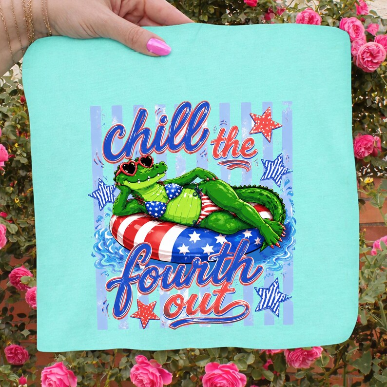 May include: A light blue square towel with a graphic of an alligator wearing sunglasses and a bikini, lounging on a red, white, and blue inner tube. The text "Chill the Fourth Out" is written above and below the alligator.