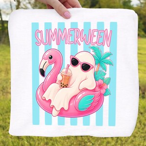 K&ouml;nnte beinhalten: Wei&szlig;es Strandtuch mit einem Cartoon-Geist mit Sonnenbrille, der auf einem rosa Flamingo-Schwimmring sitzt. Der Geist h&auml;lt ein Getr&auml;nk mit Boba. Auf dem Tuch steht das Wort "SUMMERWEEN" in rosa Buchstaben und blauen Streifen.