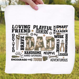 May include: White square towel featuring the word "DAD" in a camouflage pattern, with surrounding words such as "Loving", "Playful", "Hero", and "Smart". The design also includes tools and stars.