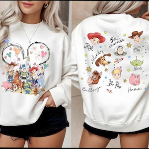 Può includere: Felpa bianca con una grafica colorata di Toy Story sul davanti e sul retro. Il design anteriore include un contorno della testa di Topolino con fuochi d'artificio e palloncini. Il retro mostra ritratti di personaggi e il testo "BUZZ LIGHTYEAR".