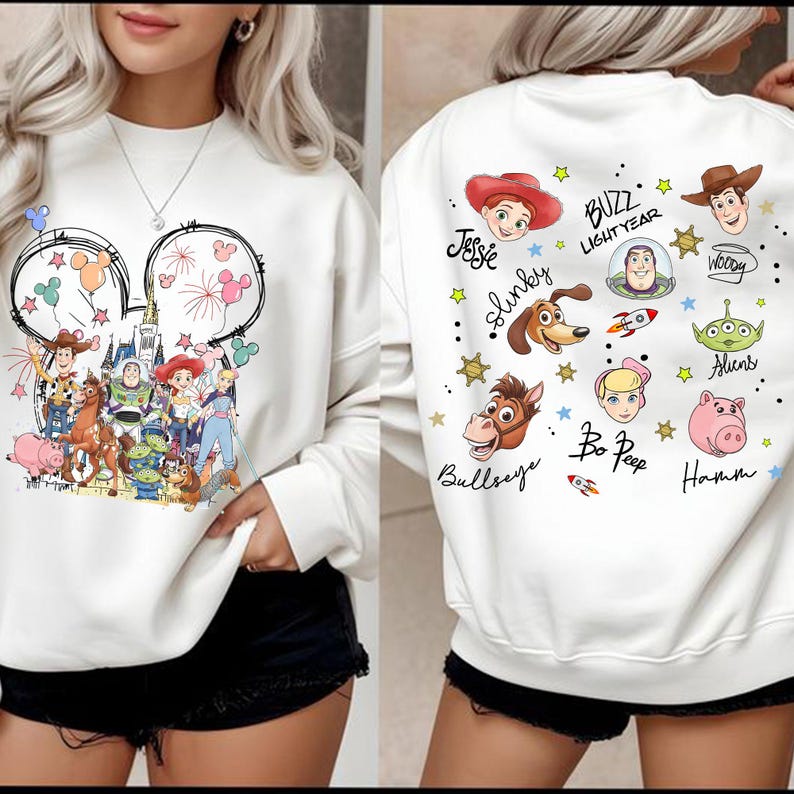 May include: White sweatshirt with a vibrant Toy Story design on the front and back. The front features a Mickey Mouse outline with characters and fireworks. The back displays character portraits and the text "BUZZ LIGHTYEAR".