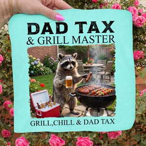 May include: A light blue sign with the text "DAD TAX & GRILL MASTER" and "GRILL, CHILL & DAD TAX". The image features a raccoon wearing sunglasses, holding a beer and a sausage, grilling food.