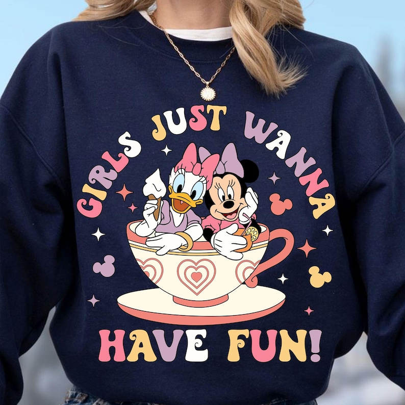 May include: A navy blue sweatshirt with a graphic of Disney's Minnie Mouse and Daisy Duck in a teacup. The text "Girls Just Wanna Have Fun!" is printed in a colorful retro font.