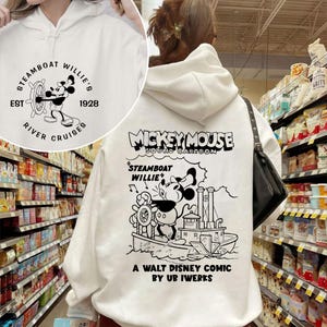 May include: White hooded sweatshirt featuring a black and white illustration of Mickey Mouse on a steamboat. The text "Mickey Mouse Sound Cartoon" is above the illustration. The text "Steamboat Willie" is above Mickey Mouse. The text "A Walt Disney Comic by Ub Iwerks" is below the illustration.