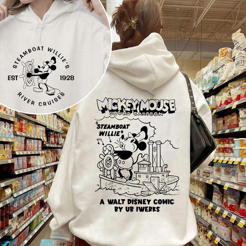 May include: White hooded sweatshirt featuring a black and white illustration of Mickey Mouse on a steamboat. The text "Mickey Mouse Sound Cartoon" is above the illustration. The text "Steamboat Willie" is above Mickey Mouse. The text "A Walt Disney Comic by Ub Iwerks" is below the illustration.
