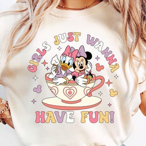 May include: A white t-shirt with a graphic of Minnie Mouse and Daisy Duck sitting in a teacup. The text "Girls Just Wanna Have Fun!" is printed in colorful letters below the image.