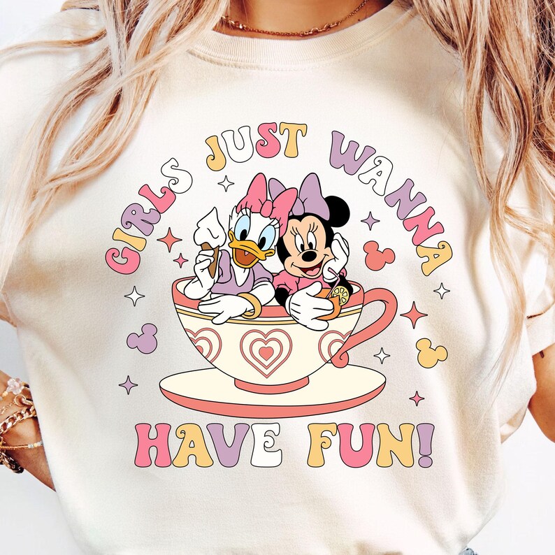 May include: A white t-shirt with a graphic of Minnie Mouse and Daisy Duck sitting in a teacup. The text "Girls Just Wanna Have Fun!" is printed in colorful letters below the image.
