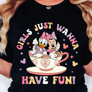 May include: Black t-shirt with a graphic of Disney's Minnie Mouse and Daisy Duck in a teacup. The text "Girls Just Wanna Have Fun!" is printed in a retro font.