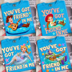 Op de afbeelding: Vier felblauwe T-shirts met de Toy Story-personages Woody, Jessie, Bo Peep en Buzz Lightyear. Elk shirt toont de tekst "YOU'VE GOT A FRIEND IN ME" samen met het personage dat in een blauwe zwemband gitaar speelt.