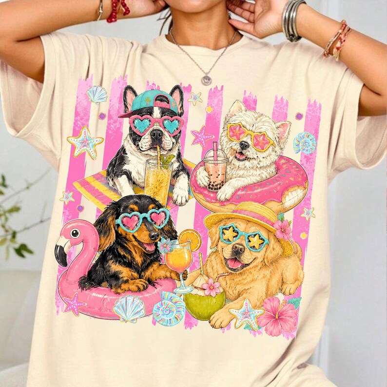 May include: Cream-colored t-shirt featuring a graphic of four dogs enjoying summer. The dogs wear sunglasses and are surrounded by beach-themed elements like a flamingo float, drinks, and starfish. Pink and white stripes form a background.