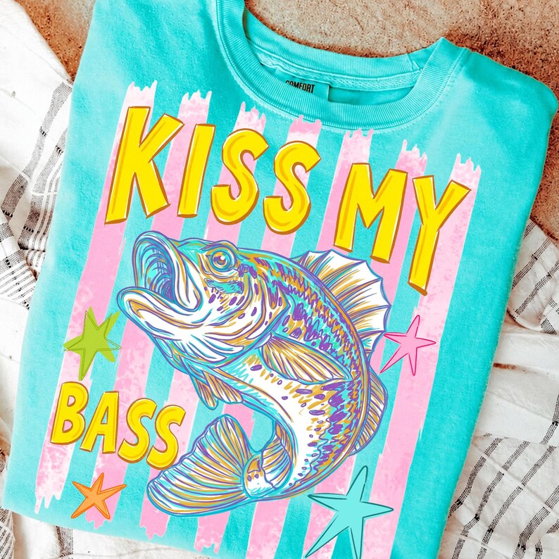 May include: A turquoise crew neck sweatshirt with the phrase "KISS MY BASS" in yellow block letters. A colorful illustration of a fish is centered below the text, with pink and white stripes and star accents.