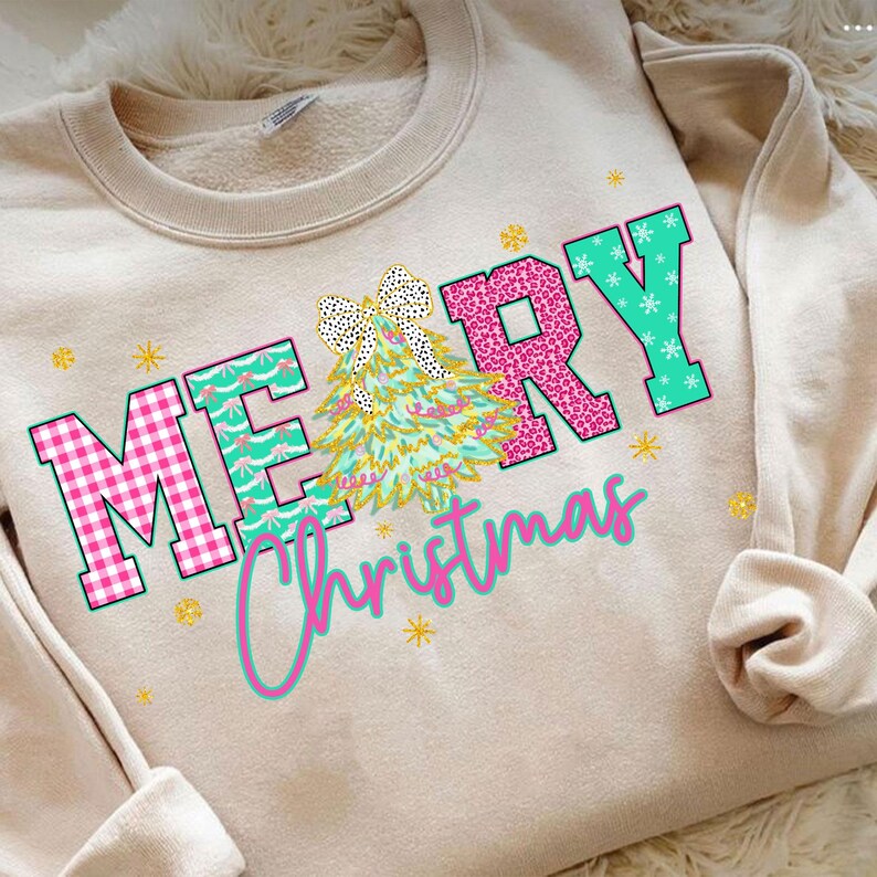 Puede incluir: Sudadera beige con las palabras "MERRY Christmas" en un dise&ntilde;o colorido. Las letras son rosas, turquesas y blancas, con un gr&aacute;fico de &aacute;rbol de Navidad en el centro. Estrellas doradas y un lazo acent&uacute;an el dise&ntilde;o.