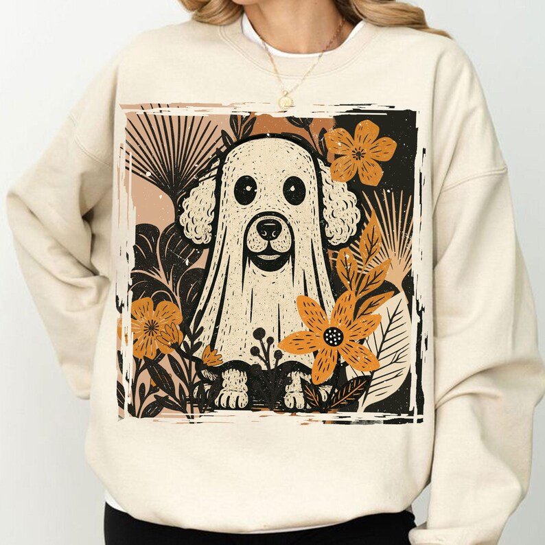Pu&ograve; includere: Felpa color crema con una grafica di un cane vestito da fantasma, circondato da fiori e foglie arancioni. Il disegno &egrave; incorniciato all'interno di un bordo rettangolare. Un design divertente e stagionale per Halloween.