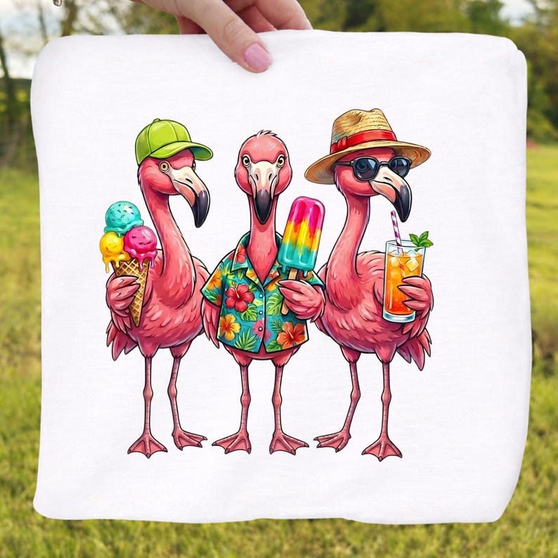 May include: A white towel featuring a whimsical illustration of three pink flamingos. One flamingo wears a green cap and holds an ice cream cone, another wears a Hawaiian shirt and holds a popsicle, and the third wears sunglasses and a straw hat, holding a drink.