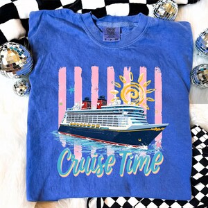 May include: A blue Comfort Colors sweatshirt with a cruise ship graphic and the words "Cruise Time." The design includes a sun, pink stripes, and stars. The shirt is a small size.