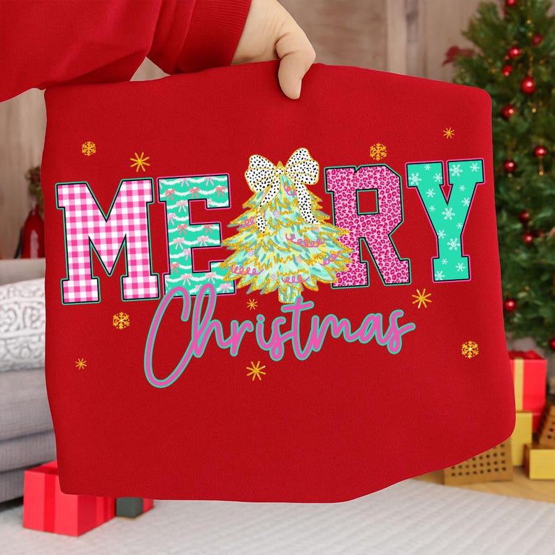 Puede incluir: Sudadera roja con tem&aacute;tica navide&ntilde;a con las palabras "MERRY Christmas" en un dise&ntilde;o colorido y estampado. La "M" es rosa a cuadros, la "E" es turquesa con un patr&oacute;n de ondas y la "R" es rosa con lunares. Un &aacute;rbol de Navidad y un lazo est&aacute;n en el centro.