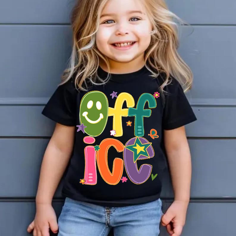 May include: Black t-shirt with the word "OFFICE" in colorful, playful letters. The "O" is a green smiley face, and the other letters are in yellow, teal, orange, and purple. The shirt is worn by a young child.
