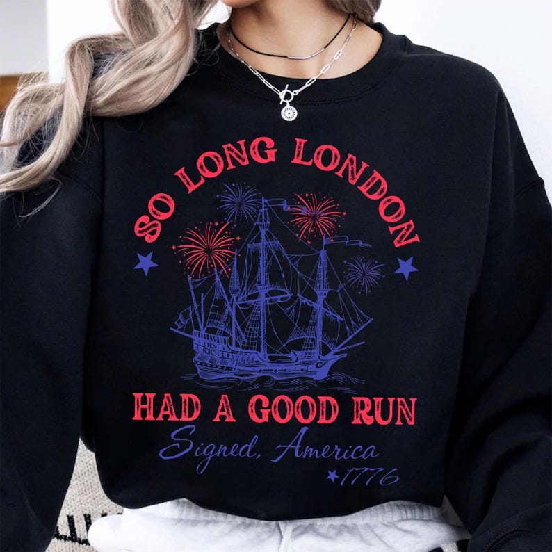 May include: Black sweatshirt with a graphic design featuring a tall ship, fireworks, and text that reads "So Long London, Had a Good Run, Signed, America, 1776". The design is in red and blue.