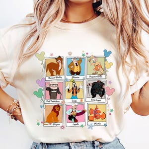 Pu&ograve; includere: Felpa color crema con una griglia di ritratti di personaggi dei cartoni animati. I personaggi includono Thomas O'Malley, Maurice, Professor Porter, Carl Fredricksen, Pippo, Re Fergus, Mufasa, Cogsworth e Marlin. Ogni ritratto &egrave; incorniciato.