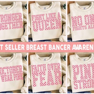 May include: Cream-colored sweatshirts with pink checkered text. The sweatshirts display phrases like "Stronger Together," "Fight Like a Queen," and "Pink Strong." The image also includes the text "Best Seller Breast Cancer Awareness."