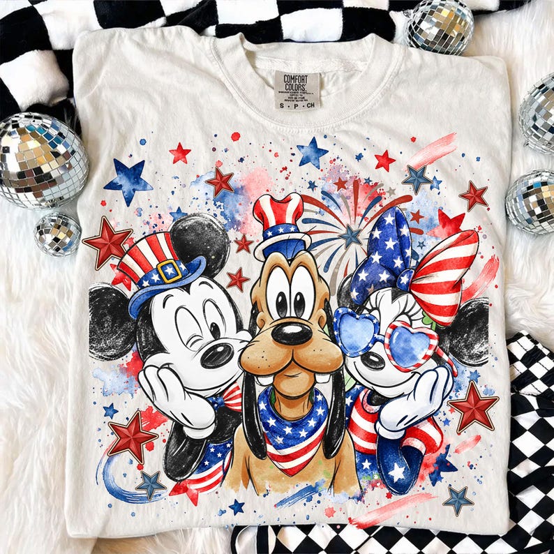 May include: White Comfort Colors t-shirt featuring Mickey Mouse, Pluto, and Minnie Mouse in patriotic attire. The design includes red, white, and blue stars, fireworks, and hats, perfect for Independence Day celebrations.