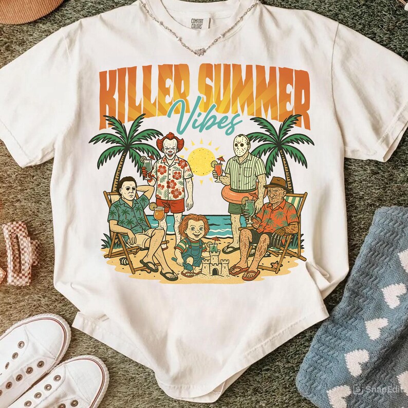 May include: White t-shirt with the text "Killed Summer Vibes" in orange and teal. The graphic features cartoon characters on a beach with palm trees, a sun, and sand. The characters are holding drinks and relaxing.